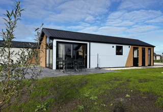 Moderne Velthorst-lodge ved The IJssel Islands i Holland med terrasse, møbler og grøn græsplæne foran.