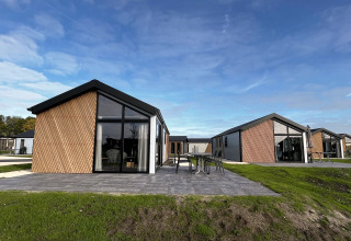 Moderne Velthorst-lodges op The IJssel Islands, Nederland, met glazen gevels en een groene omgeving.