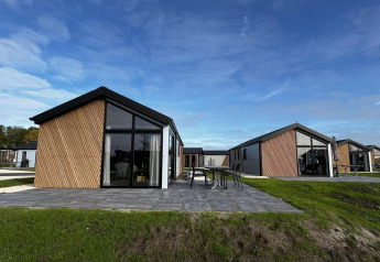 Moderne Velthorst-lodges på The IJssel Islands, Holland, med glasfacader og grønne omgivelser under blå himmel.