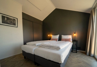 Modern ingerichte slaapkamer met tweepersoonsbedden in lodge Velthorst op de IJssel Eilanden, Nederland.
