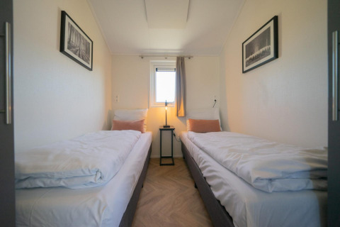 Velthorst Lodge-Zimmer auf den IJssel-Inseln, Niederlande, mit zwei Einzelbetten, Fenster und Bildern.