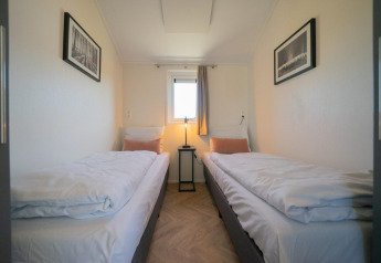 Velthorst Lodge-Zimmer auf den IJssel-Inseln, Niederlande, mit zwei Einzelbetten, Fenster und Bildern.