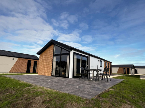 Moderne Velthorst lodge bij The IJssel Islands in Nederland met terras en tuinset onder een heldere blauwe lucht.