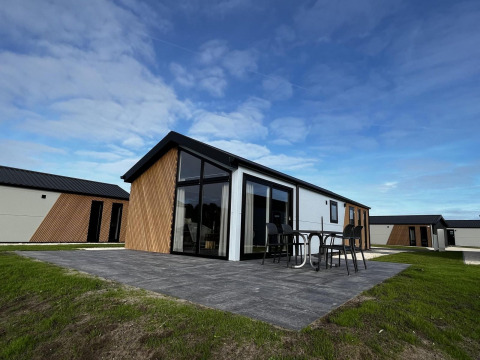 Lodge moderno Velthorst en The IJssel Islands, Países Bajos, con muebles de terraza bajo un cielo azul claro.