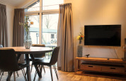 Moderne woonkamer in tiny house Berkel op de IJssel Islands, Nederland, met tv en ronde tafel.
