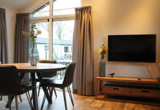 Sala moderna en la tiny house Berkel de The IJssel Islands, Países Bajos, con TV y mesa redonda.