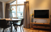 Modern living area in the Berkel tiny house at The IJssel Islands, Netherlands, with TV and round table.
