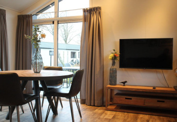 Modernes Wohnzimmer im Tiny House Berkel auf den IJsselinseln, Niederlande, mit Fernseher und Esstisch.