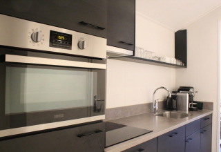 Cocina moderna en la tiny house Berkel en The IJssel Islands, Países Bajos, con horno, fregadero y cafetera.