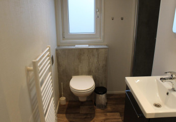 Modern bathroom in tiny house Berkel at The IJssel Islands, Netherlands, with toilet, sink, and window.