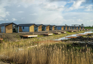 Fila de modernas casas diminutas junto al agua en The IJssel Islands, Países Bajos, bajo un cielo azul.