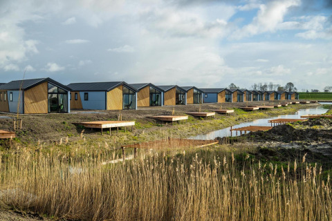 Reihe moderner Tiny Houses am Wasser auf den IJssel Islands in den Niederlanden bei bewölktem Himmel.