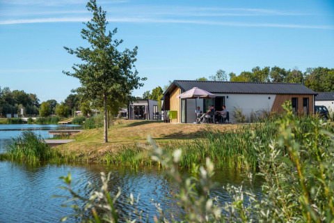 Tiny House Berkel an den IJssel Islands in den Niederlanden, am See mit Bäumen und Menschen draußen.