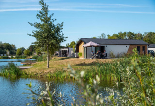 Tiny house Berkel ved IJssel Islands i Holland, ved sø med træer og folk, der nyder det udendørs.