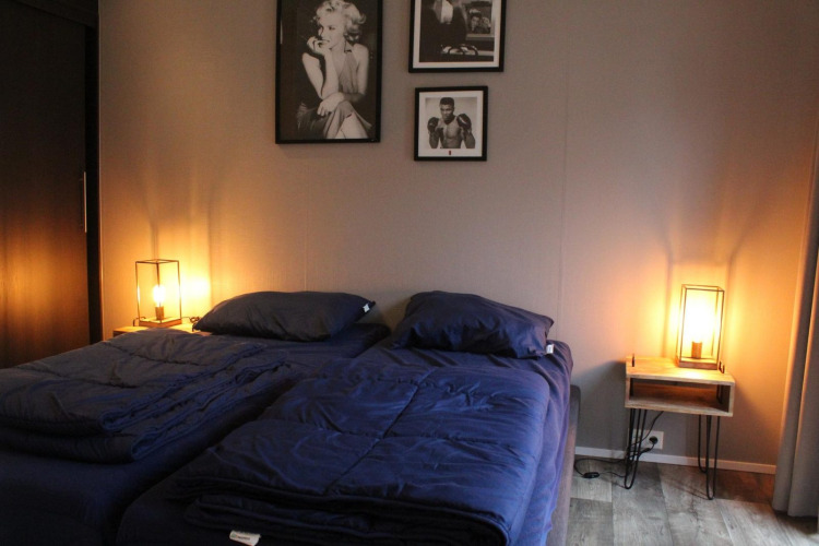 Chambre de la tiny house Berkel aux îles IJssel, Pays-Bas, avec deux lits et lumière chaleureuse.