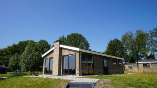 Buitenzicht van de Hackfort-lodge op een zonnige dag met gras en bomen op de achtergrond.