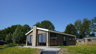 Buitenzicht van de Hackfort-lodge op een zonnige dag met gras en bomen op de achtergrond.