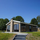 Eksteriør af Hackfort-lodge på en solrig dag med græsplæne foran og træer i baggrunden.