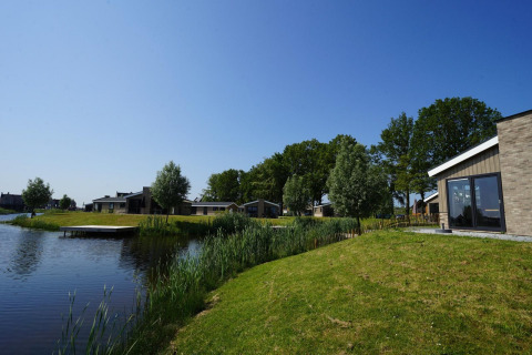 Hackfort-Lodge an den IJssel-Inseln, Niederlande mit Hütten am Wasser unter blauem Himmel.