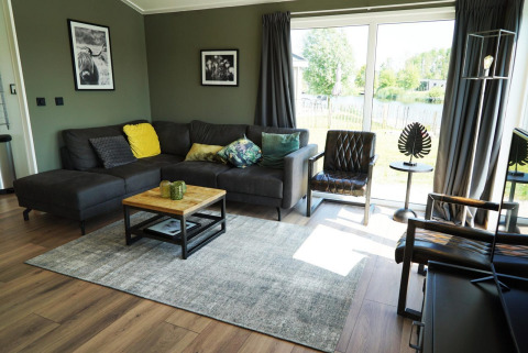 Modernes Wohnzimmer in einer Lodge auf den IJssel-Inseln, Niederlande, mit großen Fenstern und gemütlicher Einrichtung.