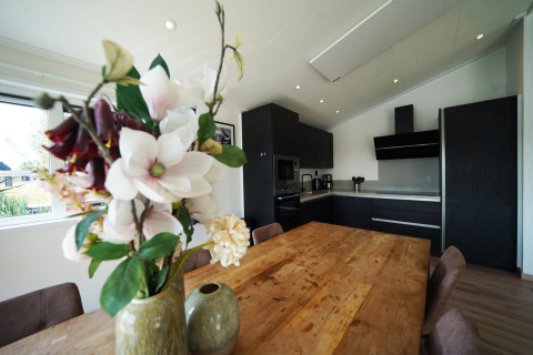 Cocina moderna y comedor en la cabaña Hackfort de las Islas IJssel, Países Bajos, con jarrón de flores.