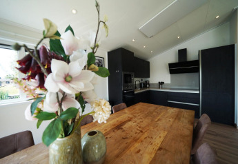 Cocina moderna y comedor en la cabaña Hackfort de las Islas IJssel, Países Bajos, con jarrón de flores.
