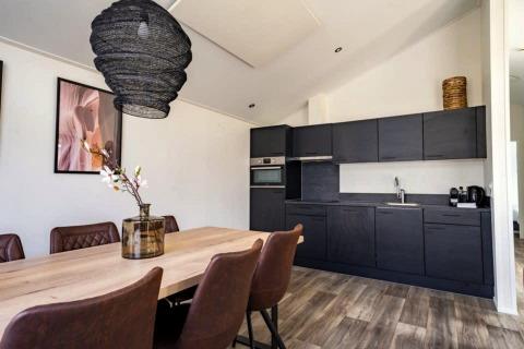 Moderne lodgekeuken en eetruimte met donkere kasten op The IJssel Islands, Nederland.