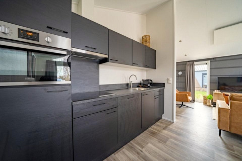Moderne keuken en woonkamer in Hackfort-lodge op The IJssel Islands in Nederland met zwarte kasten.