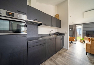 Moderne keuken en woonkamer in Hackfort-lodge op The IJssel Islands in Nederland met zwarte kasten.