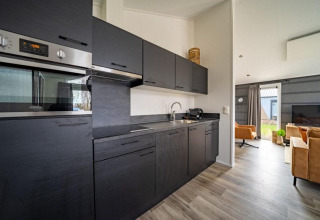 Cocina moderna y salón en la Hackfort lodge en The IJssel Islands, Países Bajos, con gabinetes negros.