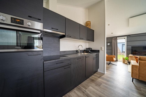 Moderne keuken en leefruimte in de Hackfort-lodge op The IJssel Islands, Nederland, met zwarte kasten.