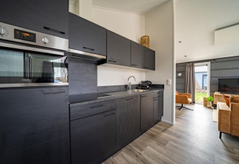 Cucina moderna e soggiorno nella Hackfort lodge alle IJssel Islands nei Paesi Bassi con mobili neri.