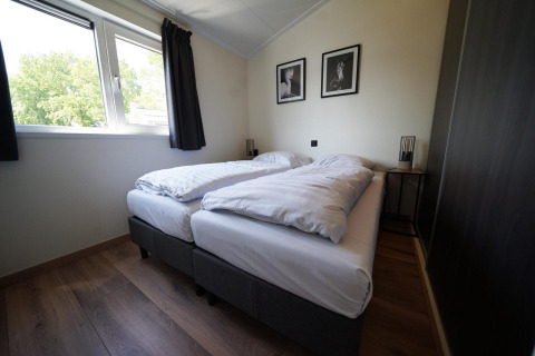 Chambre moderne à la lodge Hackfort sur les IJssel Islands, Pays-Bas, avec deux lits simples et grande fenêtre.