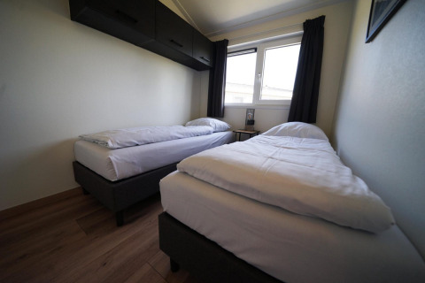 Chambre moderne à deux lits simples au lodge Hackfort sur les îles IJssel aux Pays-Bas, avec une fenêtre.