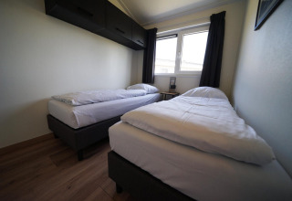 Chambre moderne à deux lits simples au lodge Hackfort sur les îles IJssel aux Pays-Bas, avec une fenêtre.