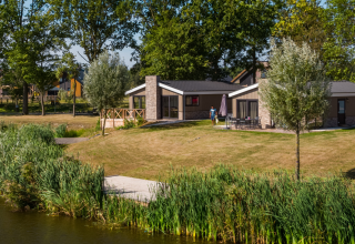 De Hackfort-lodge op De IJssel Eilanden in Nederland, eigentijds vakantiehuis aan het water te midden bomen.