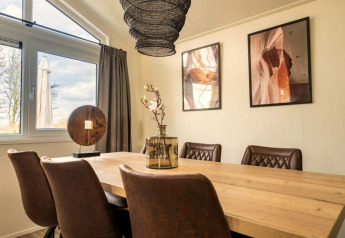 Eethoek in Hackfort lodge op de IJssel Eilanden, Nederland, met houten tafel en bruine stoelen.