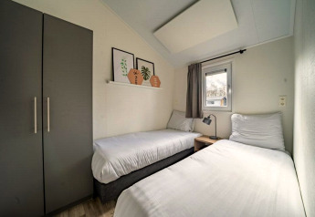 Lichte kamer met twee eenpersoonsbedden in Hackfort lodge, IJssel Eilanden, Nederland, met kast en raam.