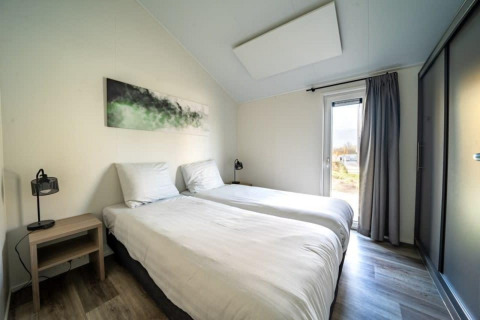 Chambre moderne de la lodge Hackfort aux Îles IJssel, Pays-Bas, avec lits jumeaux et déco sobre.
