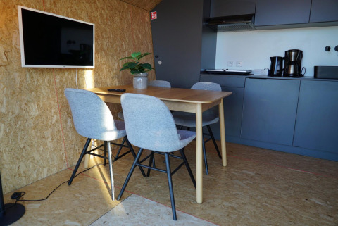 Interior moderno en Solo Retreat en las Islas IJssel, Países Bajos, con mesa, cuatro sillas y cocina pequeña.