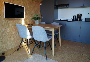 Intérieur moderne au Solo Retreat des îles IJssel, Pays-Bas, avec table à manger, quatre chaises et kitchenette.