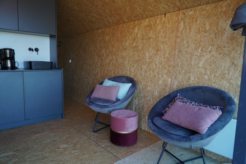 Modern lodge interior at Solo Retreat, IJssel Islands, Netherlands with cozy chairs, kitchenette, and pillows.