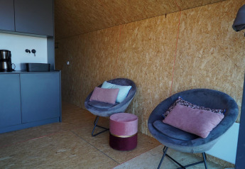 Modernes Lodge-Interieur im Solo Retreat auf den IJssel-Inseln, Niederlande mit gemütlichen Sesseln und Küchenzeile.