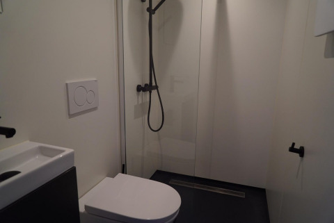 Moderne badkamer in Solo Retreat op de IJssel Eilanden in Nederland met douche, toilet en minimalistisch ontwerp.