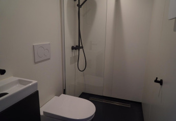 Moderne badkamer in Solo Retreat op de IJssel Eilanden in Nederland met douche, toilet en minimalistisch ontwerp.