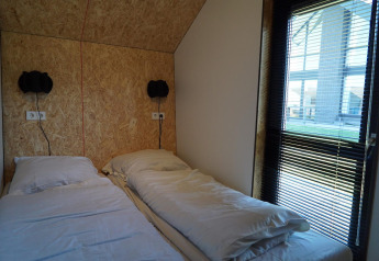 Twee eenpersoonsbedden met wit linnengoed in een kamer bij Solo Retreat op de IJssel Eilanden in Nederland.