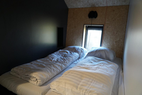 Slaapkamer in Solo Retreat, IJssel Islands, Nederland met twee eenpersoonsbedden en een klein raam.