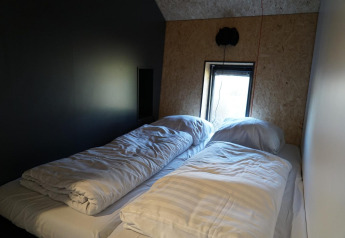 Bedroom at Solo Retreat, IJssel Islands, Netherlands with twin beds, white bedding, and small window.