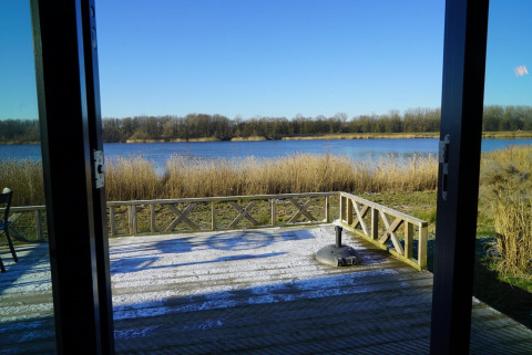 Vista desde una cabaña en Solo Retreat en las Islas IJssel, Países Bajos, mostrando terraza y lago.