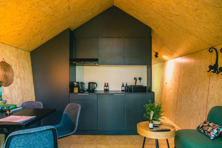 Modern Solo Retreat lodge at The IJssel Islands, Netherlands, featuring a sleek black kitchen and cozy seating.